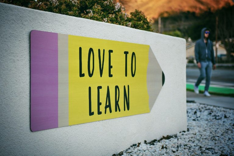 Schild "Love to learn" Gelbes Schild mit der Aufschrift "LOVE TO LEARN", im Hintergrund eine Person.